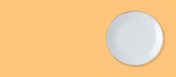 Image of Empty white ceramic plate on pale orange background, top view and space for text. Banner design