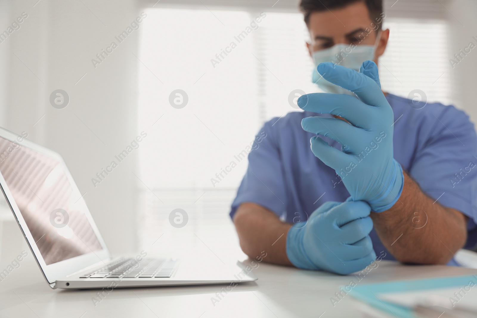 Photo of Doctor in medical gloves at table in office, focus on hands