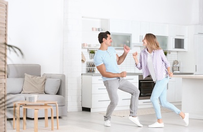 Photo of Beautiful young couple dancing in kitchen at home