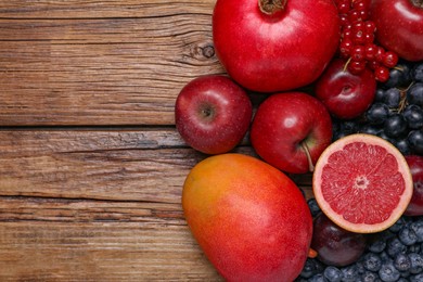 Many different fresh fruits and berries on wooden table, flat lay. Space for text