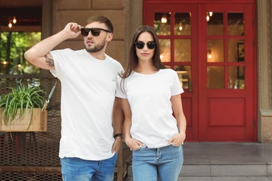 Photo of Young couple wearing white t-shirts on street