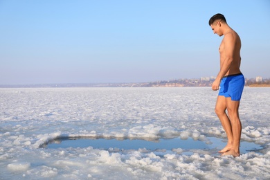 Photo of Man near ice hole on winter day. Baptism ritual