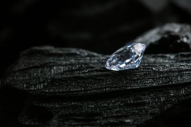 Photo of Beautiful shiny diamond on coal, closeup. Space for text