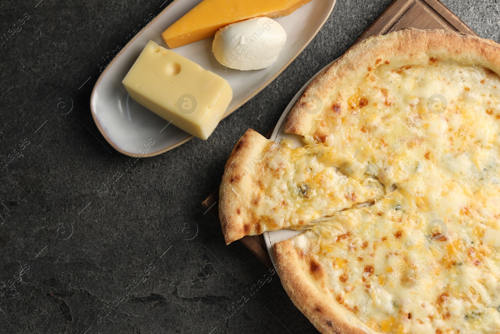 Photo of Delicious cheese pizza and different kinds of cheese on dark grey table, flat lay. Space for text