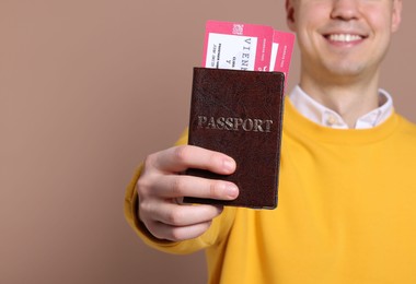 Photo of Smiling man showing passport and tickets on beige background, closeup. Space for text