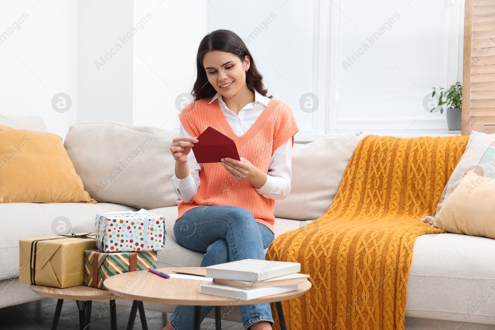 Photo of Young woman with greeting card in living room