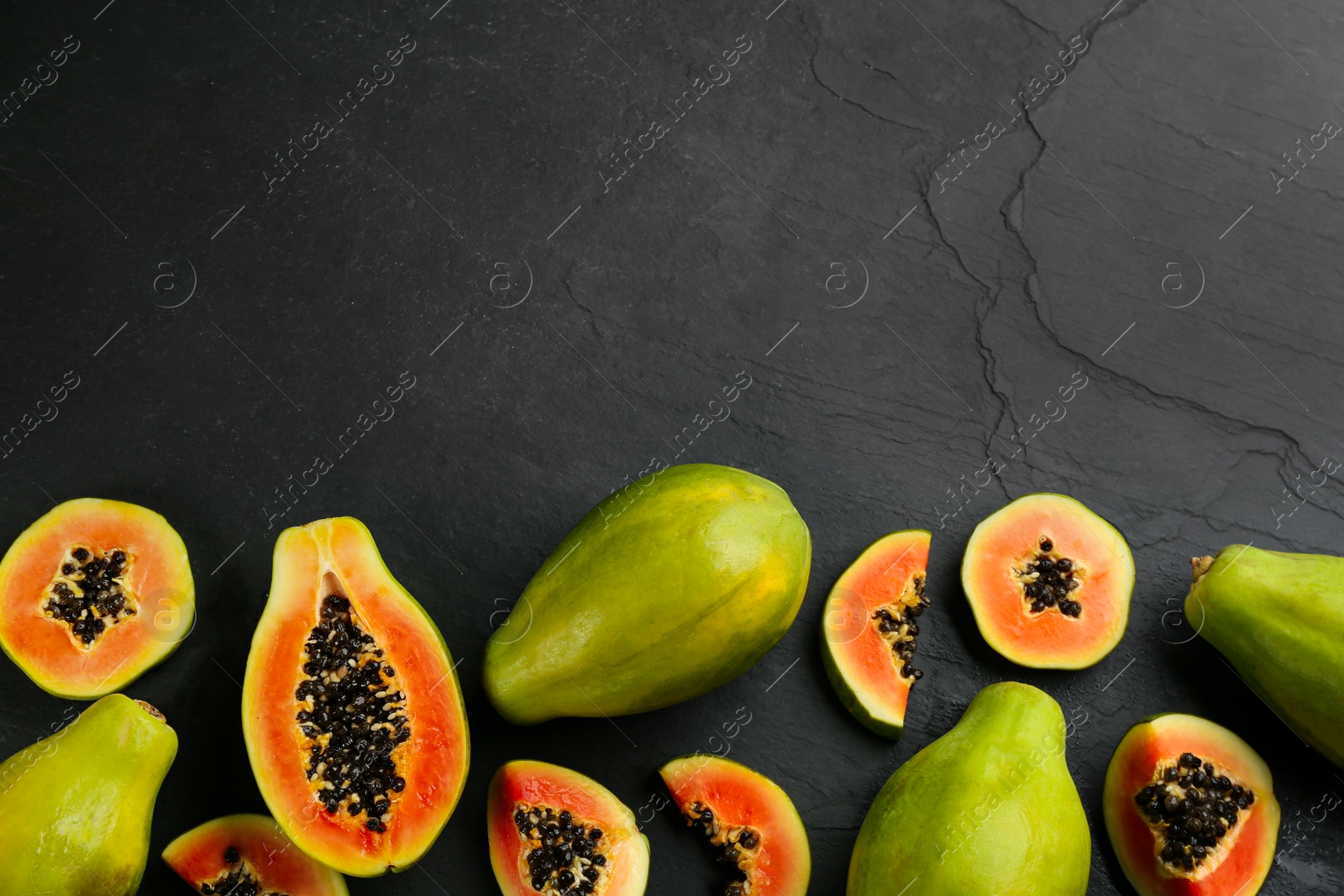 Photo of Fresh ripe papaya fruits on black background, flat lay. Space for text