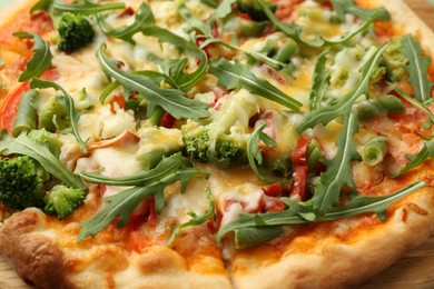 Photo of Delicious vegetarian pizza with arugula as background, closeup