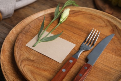 Elegant festive table setting with blank card and beautiful flower on wooden background, closeup