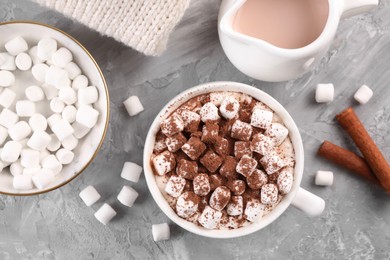 Photo of Cup of aromatic hot chocolate with marshmallows, and cocoa powder served on gray table, flat lay