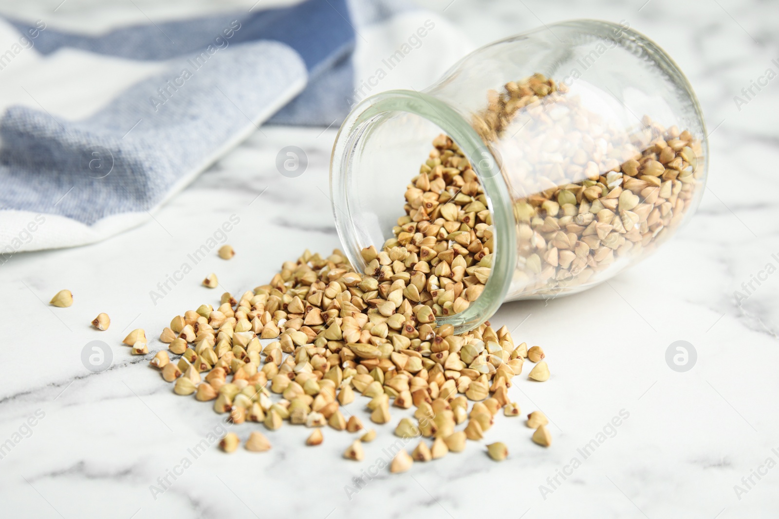 Photo of Uncooked green buckwheat grains on white marble table