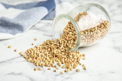 Uncooked green buckwheat grains on white marble table