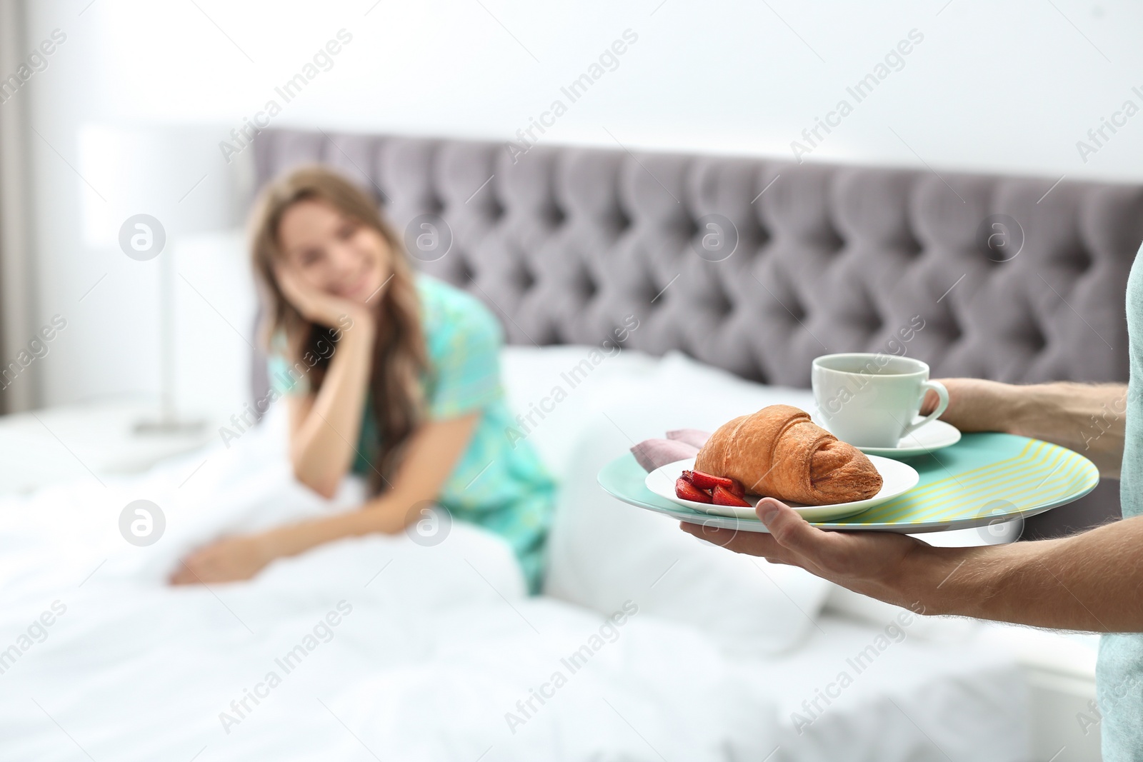 Photo of Young man bringing romantic breakfast to his girlfriend in bed at home