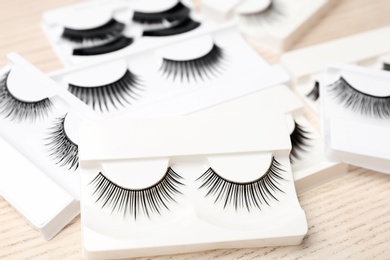 Photo of Different types of false eyelashes in packs on wooden background