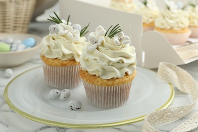 Photo of Tasty Easter cupcakes with vanilla cream on white marble table