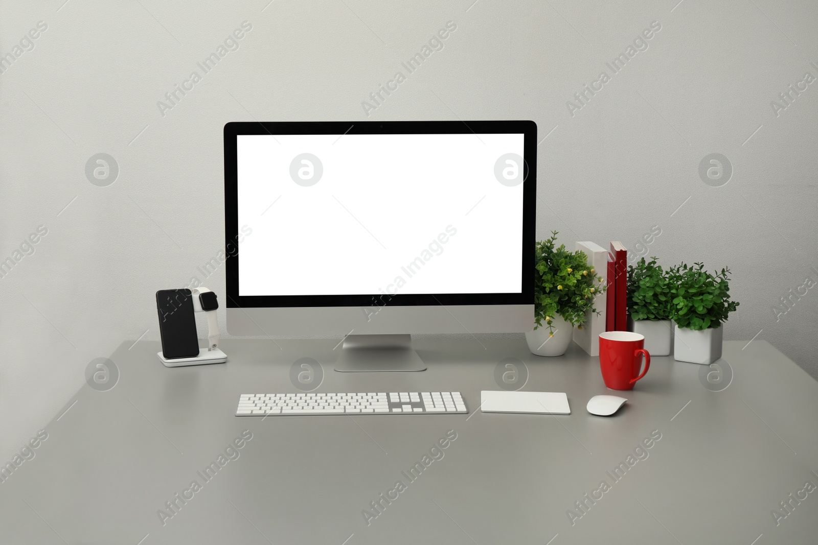 Photo of Modern workplace with computer, charging devices and houseplants. Interior design