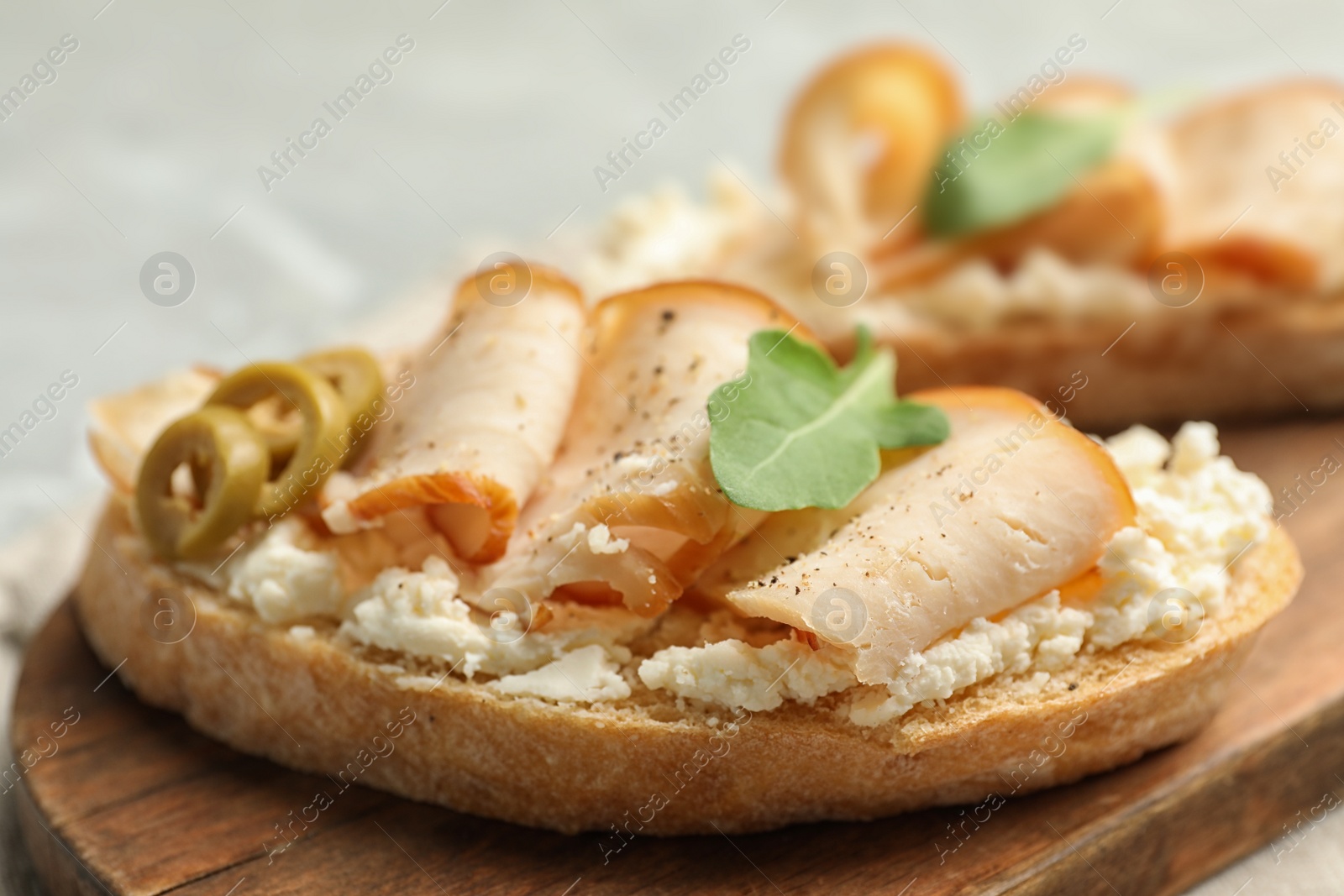 Photo of Board with delicious chicken bruschettas on table, closeup