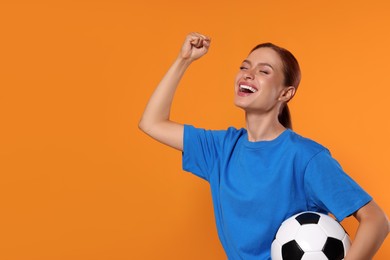 Happy fan with football ball on orange background, space for text