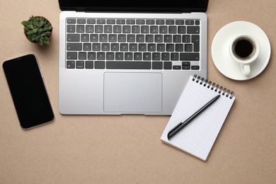 Photo of Modern laptop, notebook and cup of coffee on beige table, flat lay. Space for text