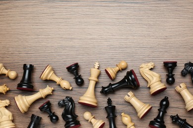Photo of Many different chess pieces on wooden table, flat lay. Space for text