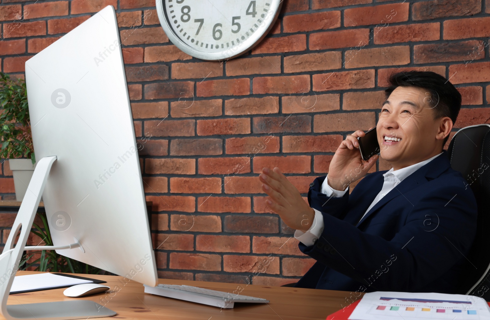 Photo of Happy boss talking on phone in his office