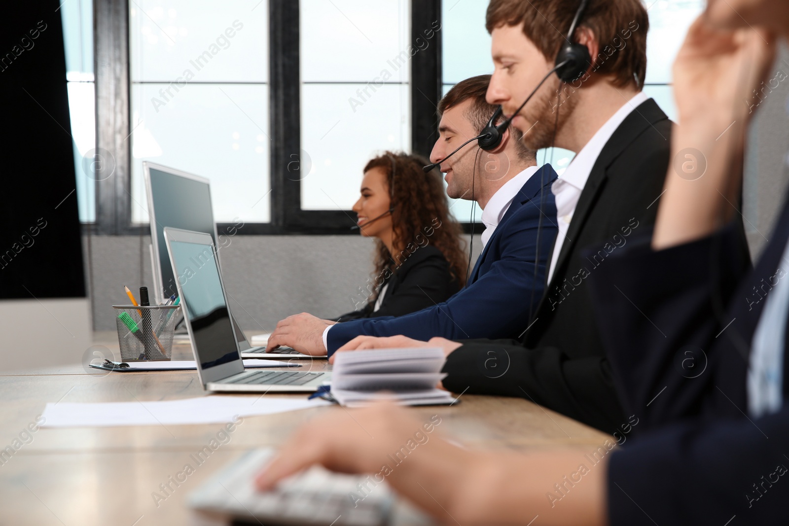 Photo of Team of technical support with headsets at workplace