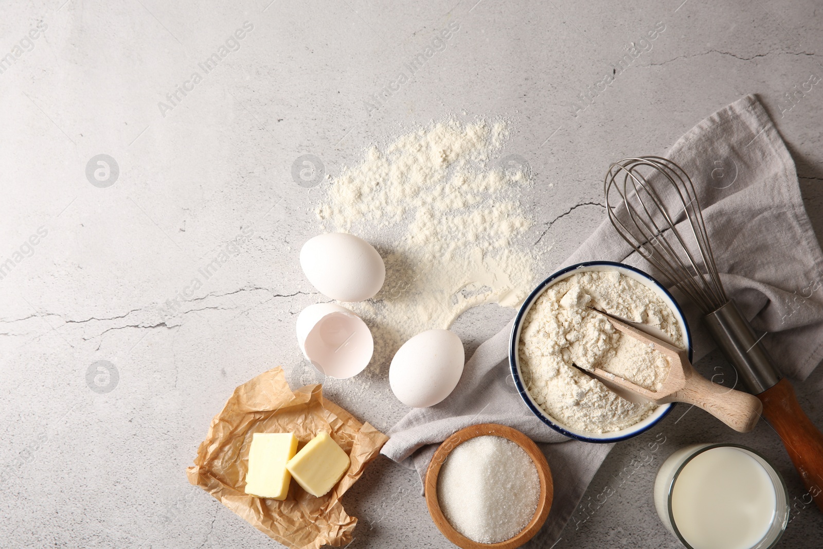 Photo of Different ingredients for dough and whisk on light textured table, flat lay. Space for text