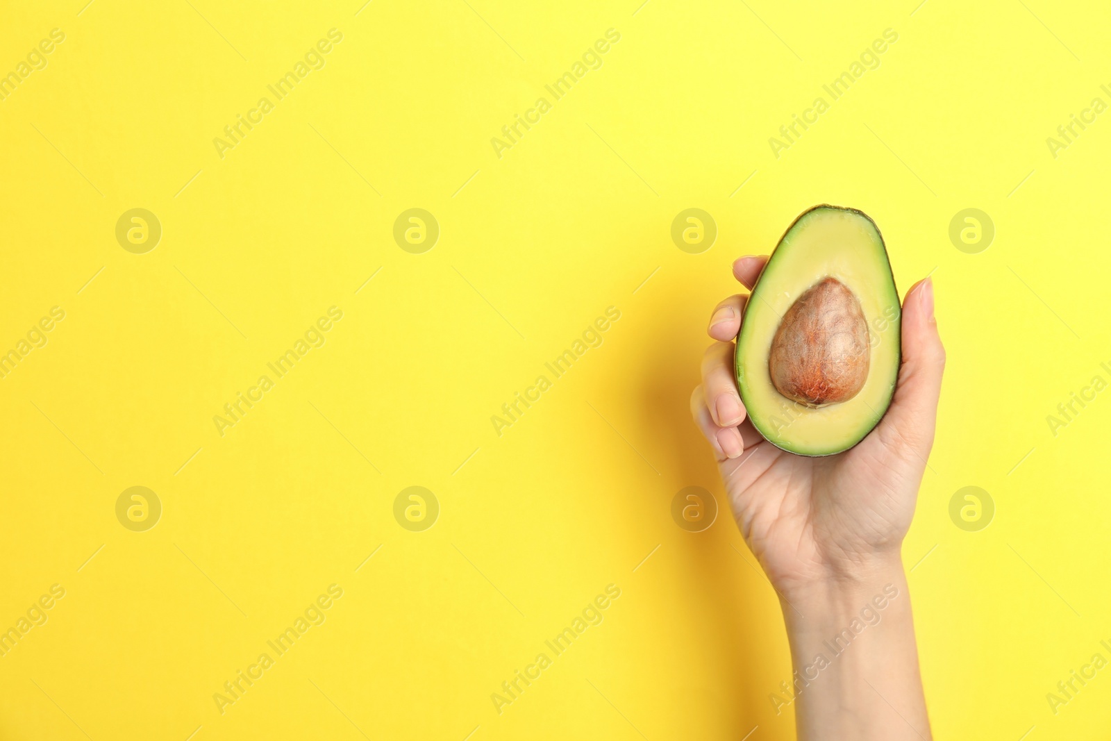 Photo of Woman holding ripe cut avocado on color background