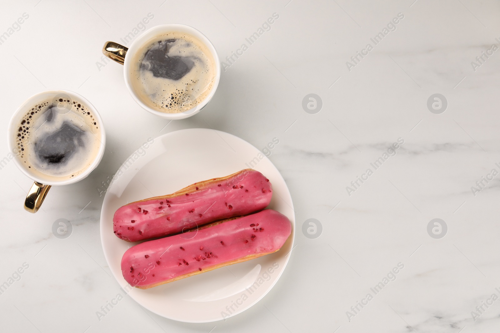 Photo of Tasty glazed eclairs and cups of coffee on white marble table, flat lay. Space for text