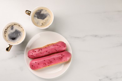 Tasty glazed eclairs and cups of coffee on white marble table, flat lay. Space for text