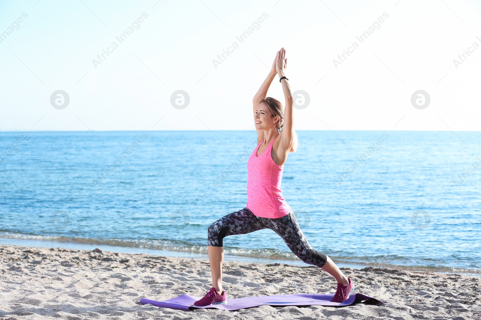 Photo of Young woman doing fitness exercises on beach in morning