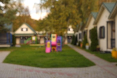 Photo of Beautiful houses and playground outdoors, blurred view. Real estate for rent