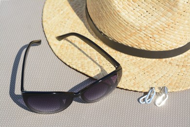 Stylish hat, sunglasses and jewelry on grey surface, closeup