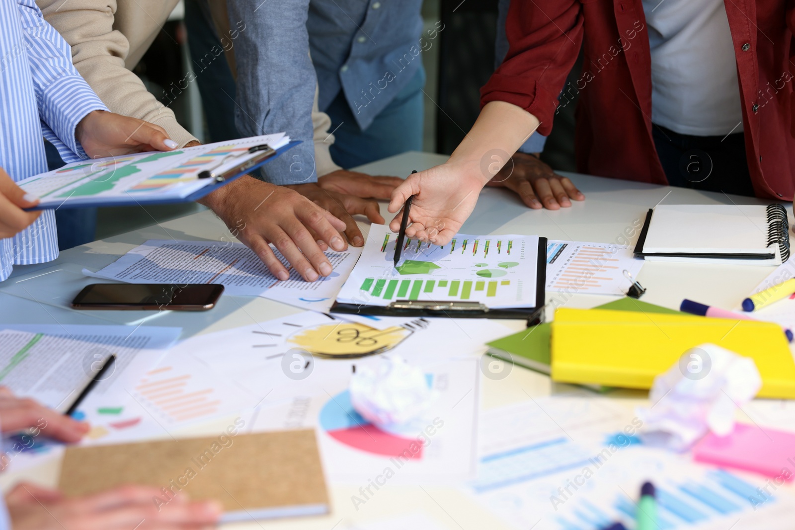 Photo of Team of employees working with charts at table, closeup. Startup project