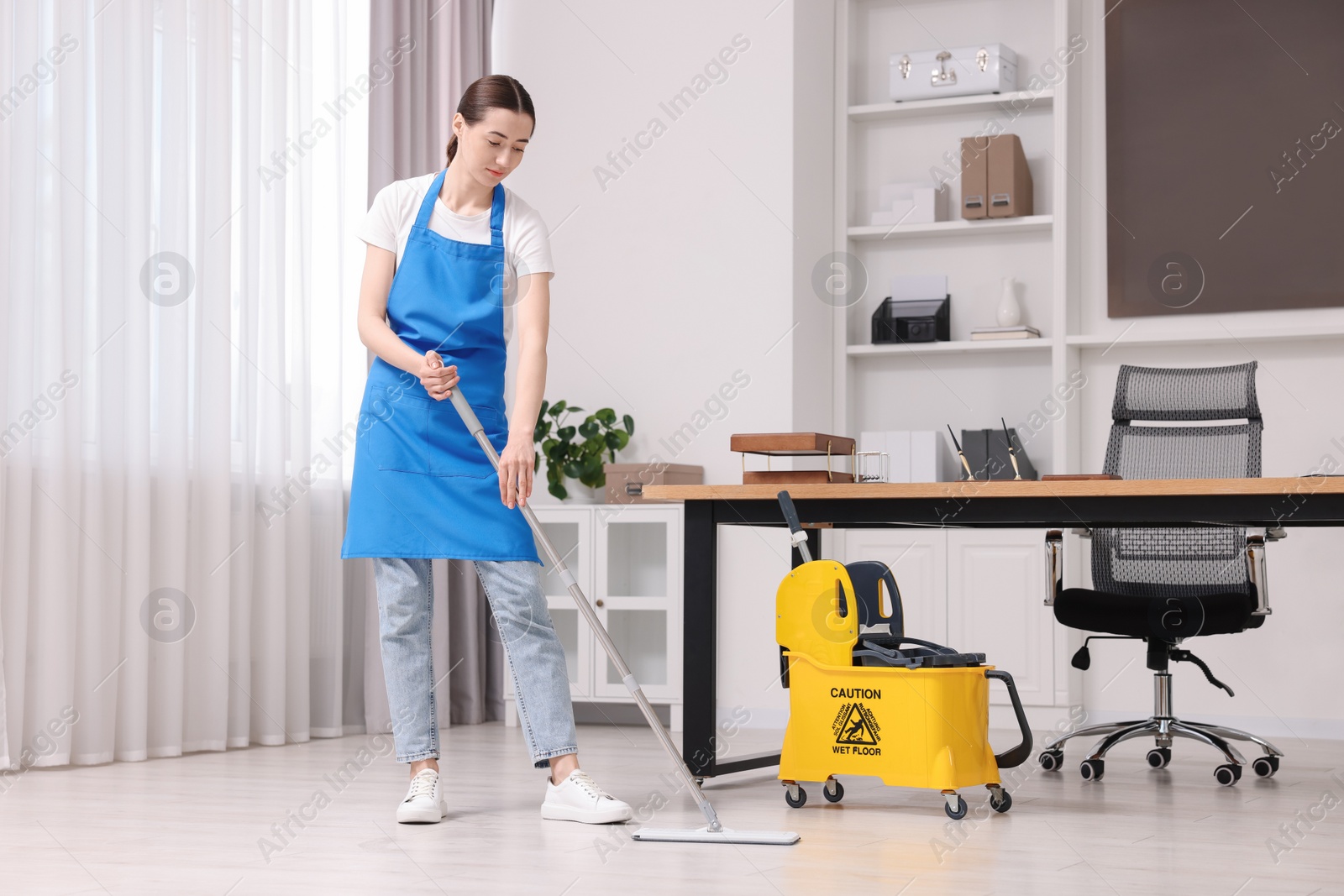 Photo of Cleaning service. Woman washing floor with mop in office