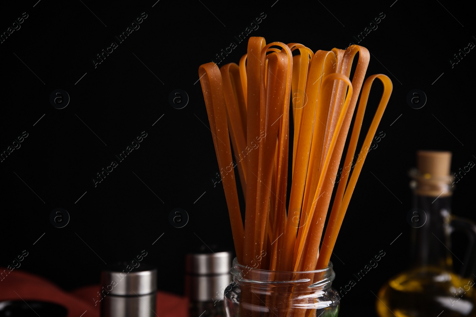 Photo of Uncooked buckwheat noodles on black background, closeup. Space for text