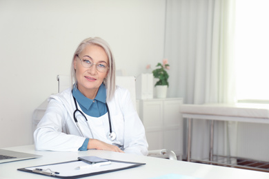 Portrait of mature female doctor in white coat at workplace