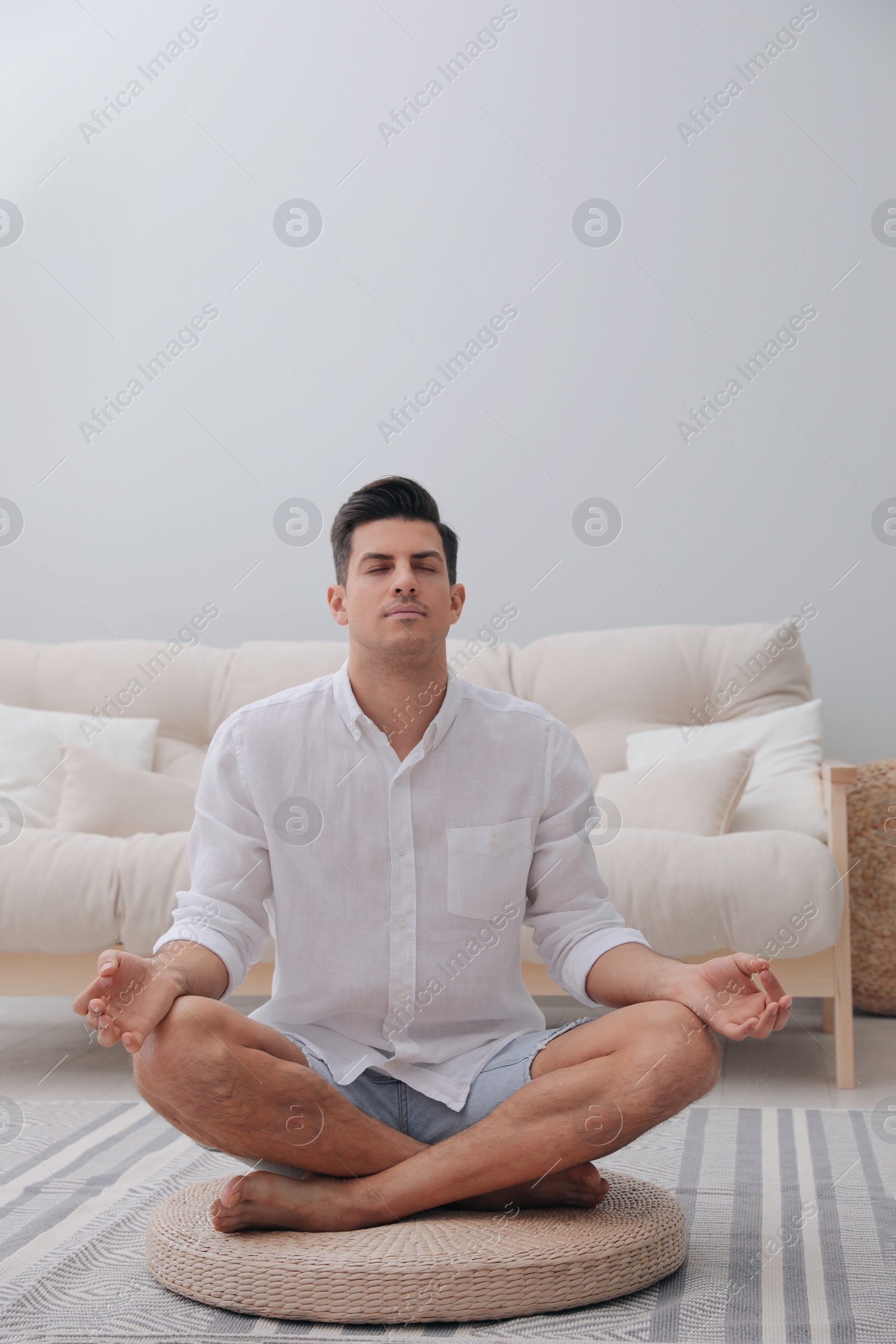 Photo of Man meditating on wicker mat at home