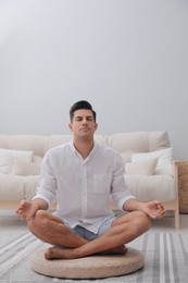 Man meditating on wicker mat at home