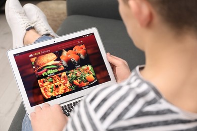 Photo of Man using tablet for ordering food online at home, closeup. Concept of delivery service