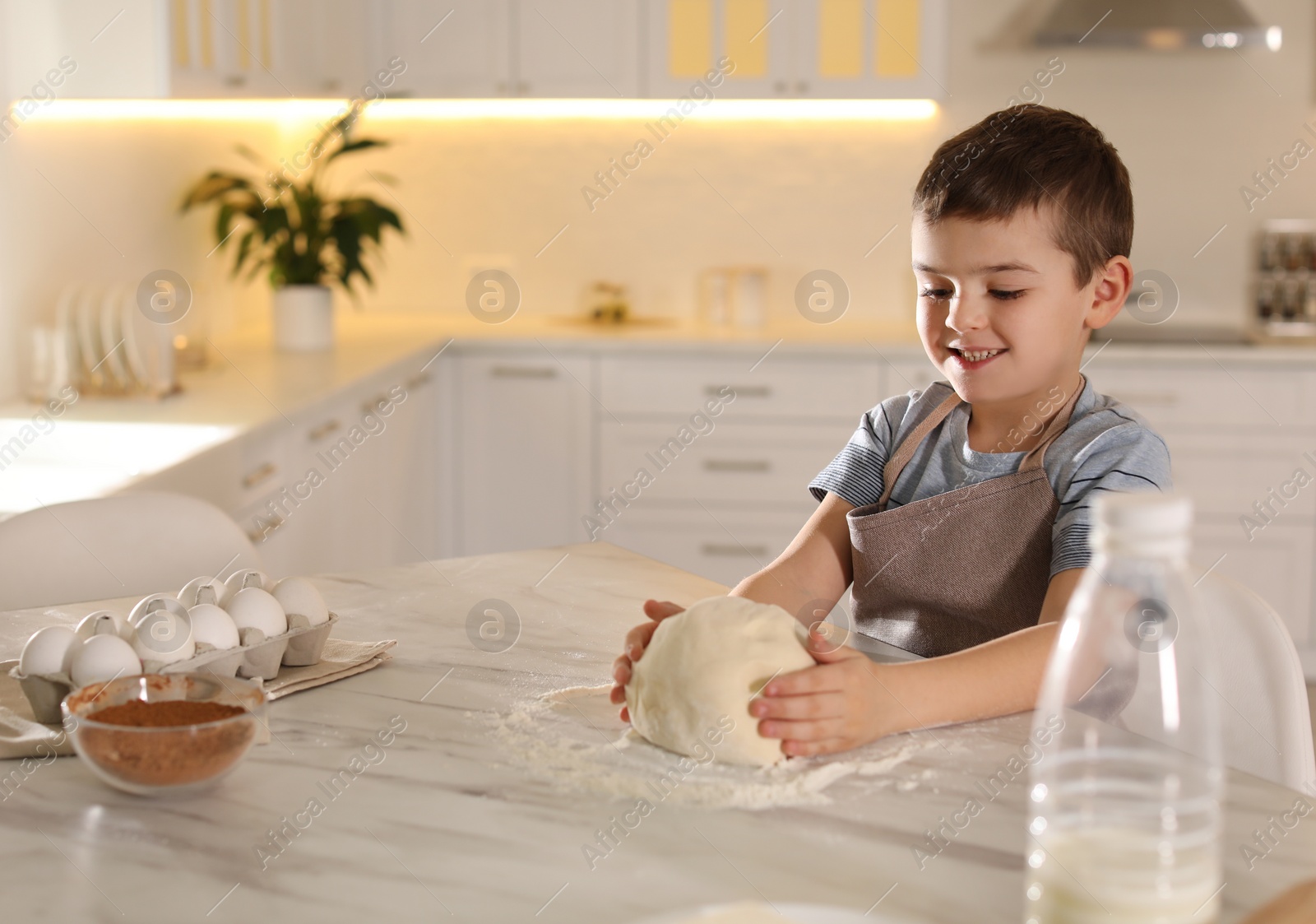 Photo of Cute little boy with dough at table in kitchen. Cooking pastry