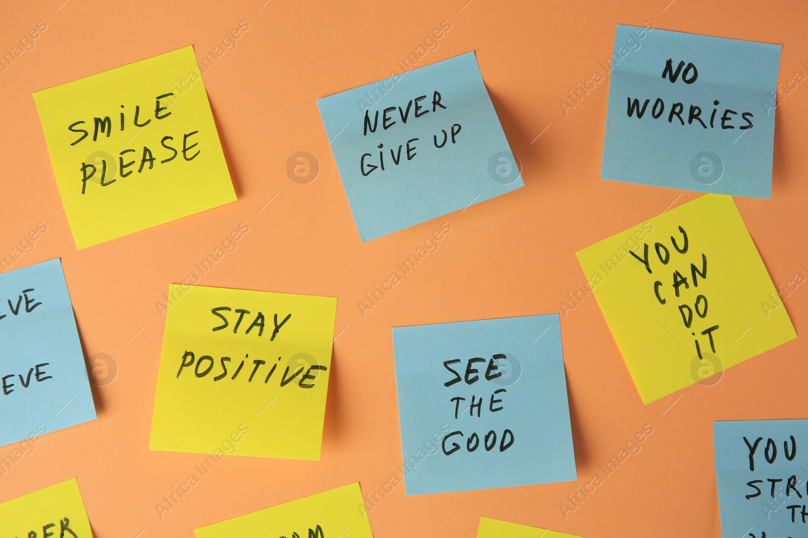 Photo of Paper notes with life-affirming phrases on pale orange background