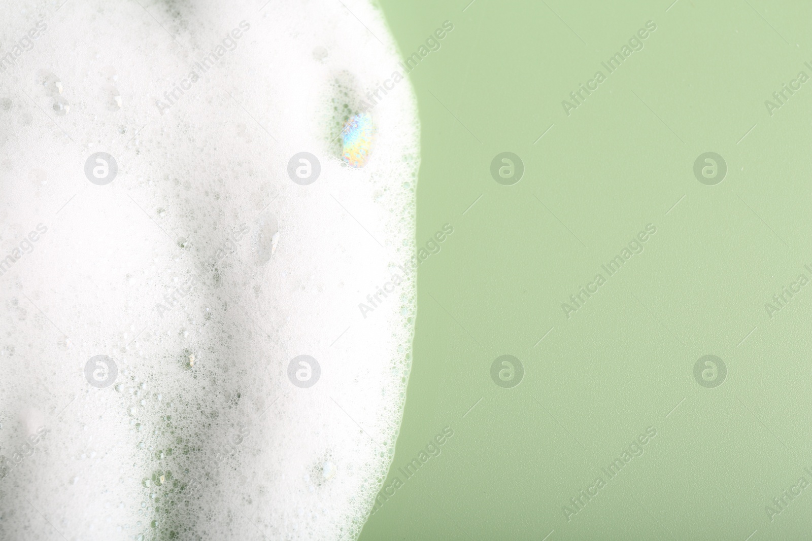 Photo of White fluffy foam on green background, top view. Space for text