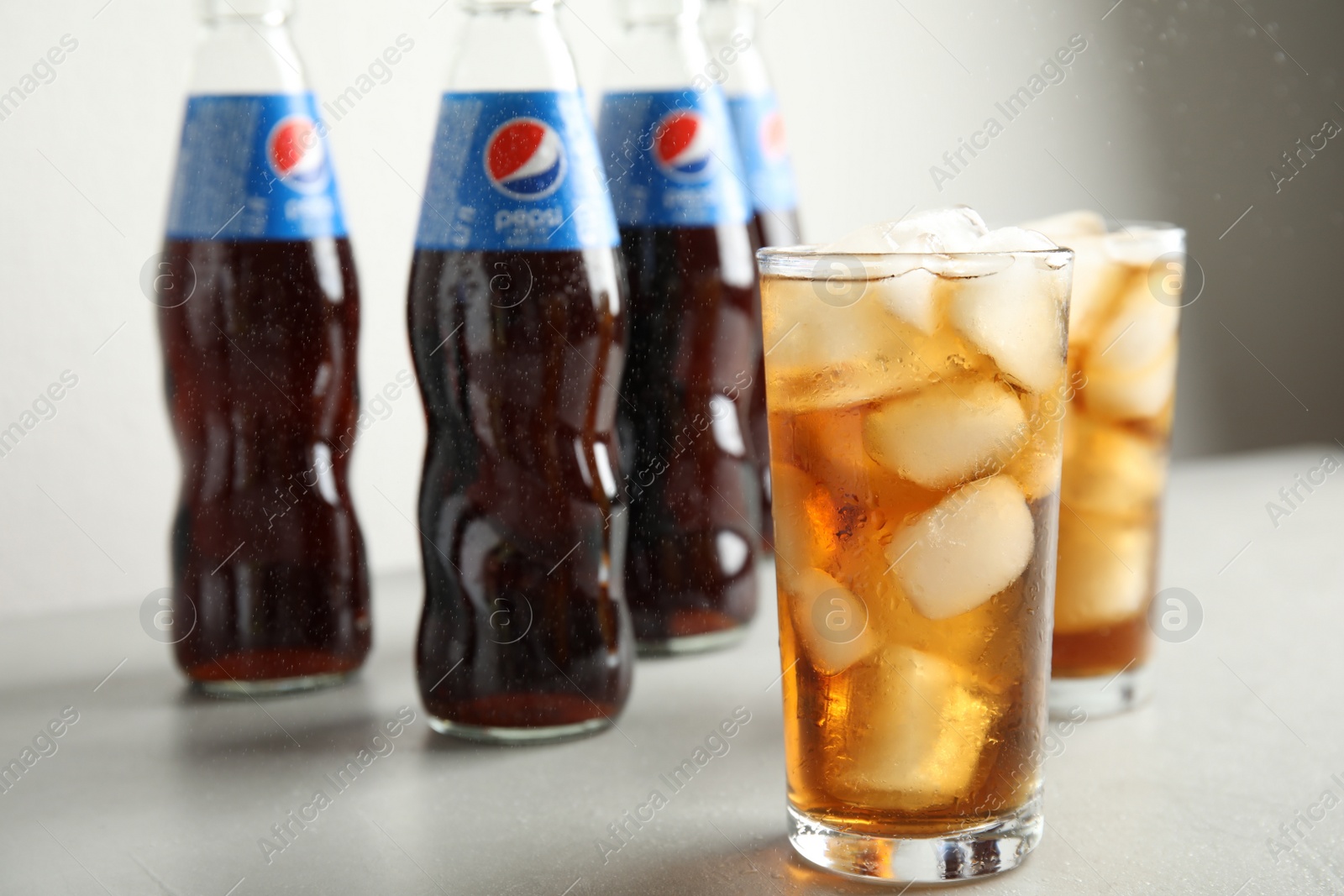 Photo of MYKOLAIV, UKRAINE - FEBRUARY 10, 2021: Glasses and bottles of Pepsi on light table