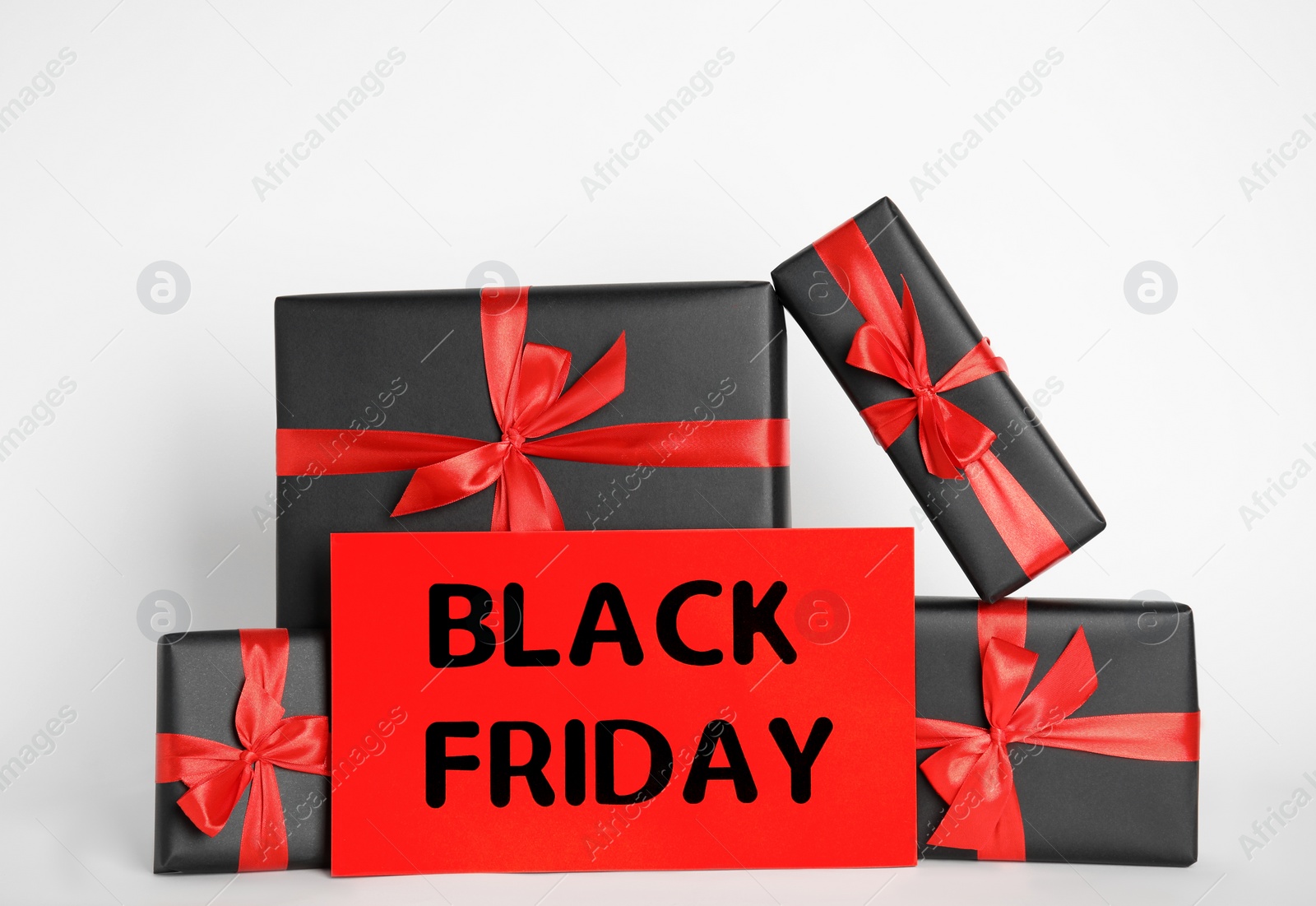 Photo of Many gift boxes and sheet of paper with words Black Friday on white background