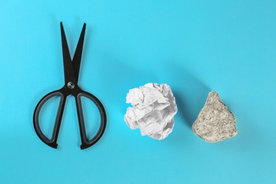 Flat lay composition with rock, paper and scissors on light blue background