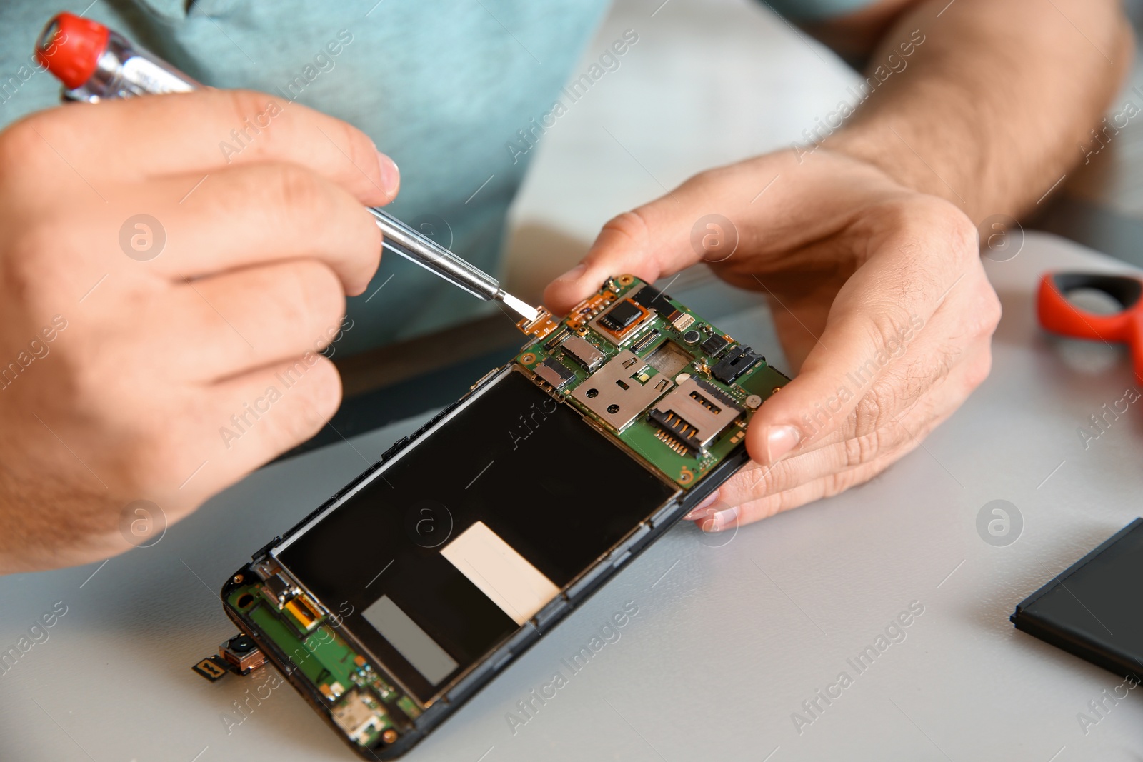 Photo of Technician repairing mobile phone at table, closeup