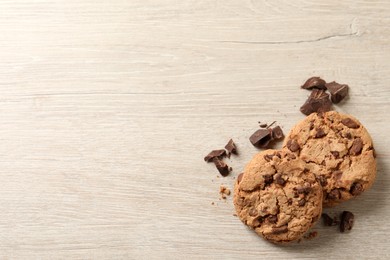 Photo of Delicious chocolate chip cookies on wooden table, flat lay. Space for text