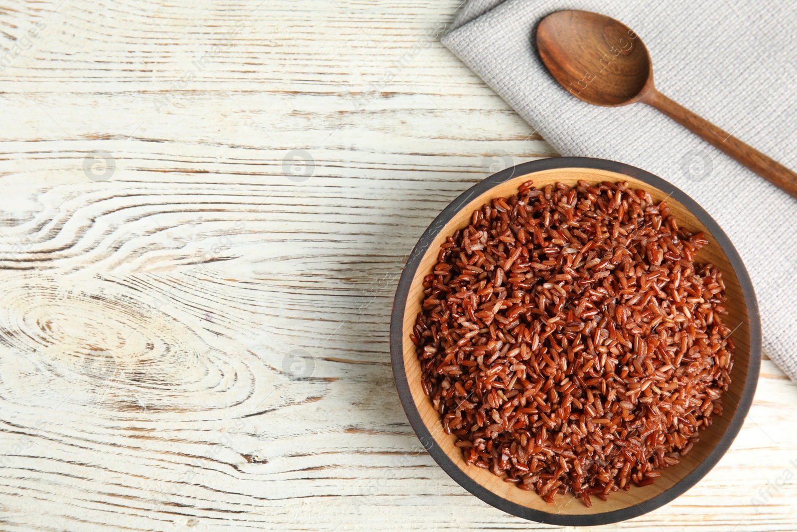 Photo of Flat lay composition with delicious cooked brown rice on white wooden table. Space for text