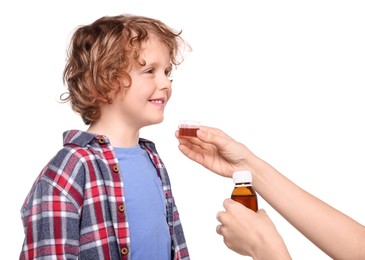 Photo of Mother giving cough syrup to her son against white background, closeup